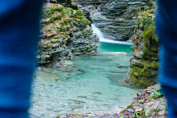 A hiker is looking at the clear waters of the Rui stream, Mel, Belluno, Italy