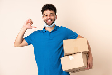 Young delivery Moroccan man isolated on beige background proud and self-satisfied