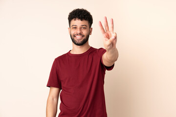 Fototapeta premium Young Moroccan man isolated on beige background happy and counting three with fingers