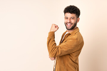 Young Moroccan man isolated on beige background celebrating a victory