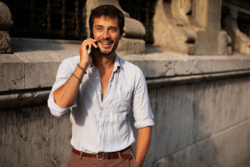 Young modern man using the phone outdoors. Fashion happy man enjoy outdoors..