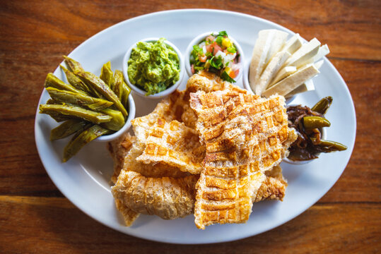 Mexican pork rind. Nopales and guacamole. Mexican cuisine on wooden background. The concept of traditional Mexican food. Mexican chicharron