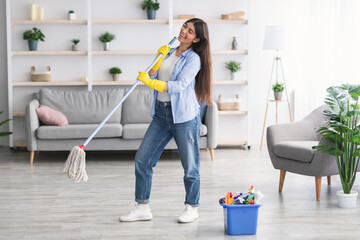 Portrait of woman cleaning floor singing holding mop