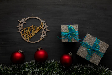 Christmas background- with gold sign, red spheres and silver gifts with blue bow on black background