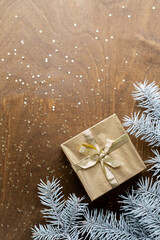 Fototapeta na wymiar a golden gift box on a wooden table with gold spangles in the shape of stars, among the fir branches