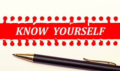 Pen and white torn paper strip on a bright red background with the text KNOW YOURSELF
