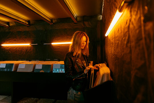 Woman choosing vinyl record in dark store