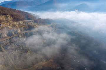 Aerial top view of landscape morning fog on mountain with quarry extracting mine industry