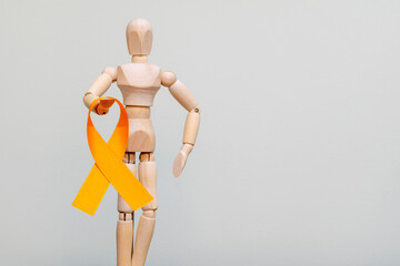 wooden dummy with orange ribbon. campaign to prevent skin cancer, melanoma