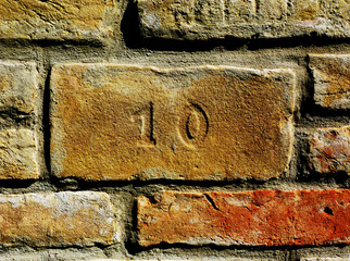 textured light brown and yellow brick wall pattern closeup. gray mortar joint. rough clay texture. running bond pattern. construction industry and architecture concept. exposed brick fence background