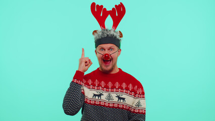 Eureka. Man in Christmas sweater deer antlers make gesture raises finger came up with creative plan feels excited with good idea, inspiration motivation isolated on blue background. Happy New Year