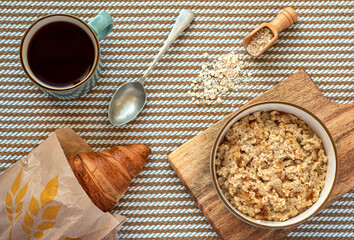 Food photography of breakfast, oatmeal porridge, croissant, mug of tea, spoon