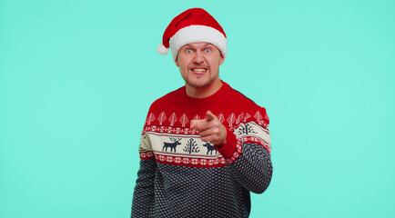 Quarrel. Displeased man in Christmas sweater gesturing hands with irritation and displeasure, blaming scolding for failure, asking why this happened isolated on blue wall background. Happy New Year