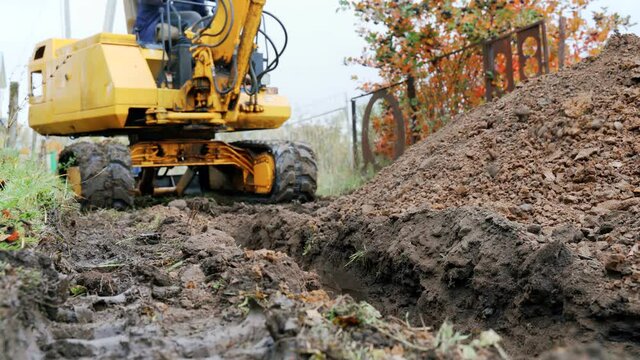 An excavator digs a trench to lay a pipeline. A small excavator is doing earthworks.