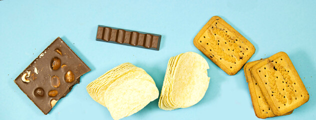 chocolate bars and salt chips with cookies isolated on blue background