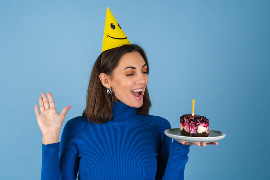 Young Woman In Golf On A Blue Background Celebrates A Birthday, Holds A Piece Of Cake, In A Great Mood, Happy, Excited