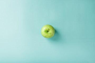 One green apple on a green background with a minimalistic composition.