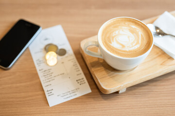 Cappuccino coffee in the cafe with money changes and bill on the table