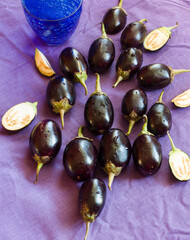 Overhead view,close-up of fresh,juicy aubergine also known as egg plant vegetable.scattered on dark violet background.Copy space.