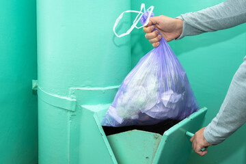 Throwing garbage into the garbage chute, a man's hand with a garbage bag.