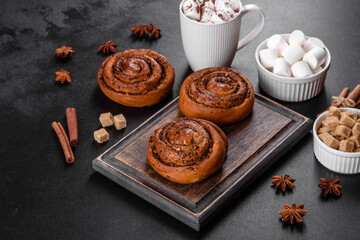 Freshly baked cinnamon roll with spices and cocoa filling on a black background