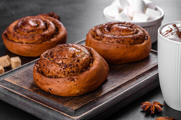 Freshly baked cinnamon roll with spices and cocoa filling on a black background
