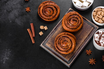 Freshly baked cinnamon roll with spices and cocoa filling on a black background