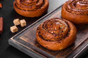 Freshly baked cinnamon roll with spices and cocoa filling on a black background