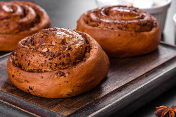 Freshly baked cinnamon roll with spices and cocoa filling on a black background