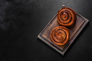 Freshly baked cinnamon roll with spices and cocoa filling on a black background