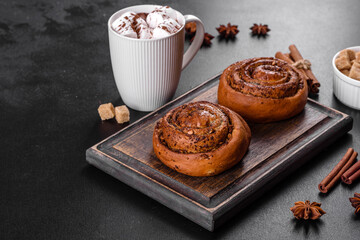Freshly baked cinnamon roll with spices and cocoa filling on a black background