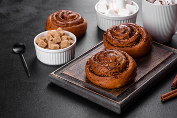 Freshly baked cinnamon roll with spices and cocoa filling on a black background