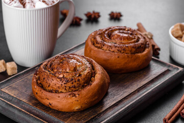 Freshly baked cinnamon roll with spices and cocoa filling on a black background
