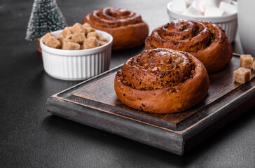 Freshly baked cinnamon roll with spices and cocoa filling on a black background