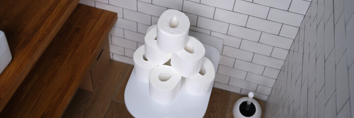 Many rolls of white paper are on toilet in restroom