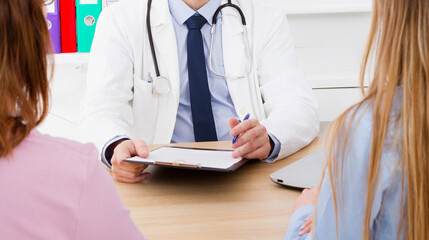 Doctor is talking with woman patient and sitting in medical office - obrazy, fototapety, plakaty