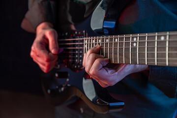Male hands playing electric guitar. Musician man with black guitar at a rock concert