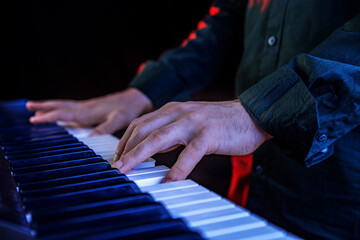 Male hands playing electric Digital Piano. Musician man with black guitar at a rock concert