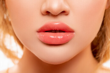Sexy Lips. Part of Face, Young Woman close up. Perfect plump Lips bodily Lipstick. Peach Color of Lipstick on Large Lips. Perfect Makeup. Beautiful Lips Close-up. Makeup. Lip shiny Lipstick.          - obrazy, fototapety, plakaty