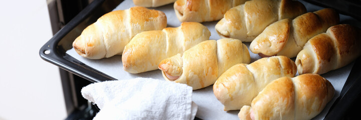 Woman chef taking out baking sheet with delicious buns from oven closeup