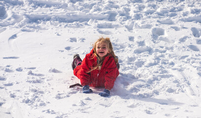 Fototapeta na wymiar Funny little girl walking outdoors on winter day. Excited christmas holiday. Cute girl laying in snow.