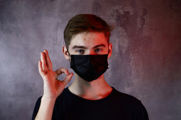 handsome teenage boy in protective medical shows ok gesture