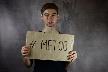 young man holds a poster, a cardboard with the text metoo