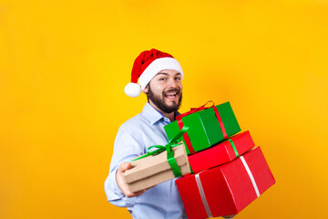 Portrait of young Latin man holding Christmas gift box on a yellow background in Mexico Latin America