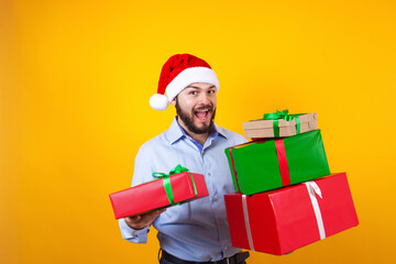 Portrait of young Latin man holding Christmas gift box on a yellow background in Mexico Latin America