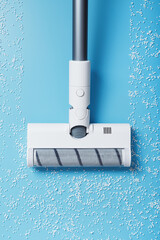 The turbo brush of the vacuum cleaner cleans white balls, top view on a blue background. The concept of cleanliness and cleaning. - obrazy, fototapety, plakaty