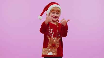 Funny child girl kid in red New Year sweater raises thumbs up agrees with something or positive reply recommends advertisement likes good on violet background. Happy Christmas celebration holidays