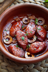 Chorizo sausage roasted in red wine with green olives and garlic. Hot tapas dish in Spanish cuisine.