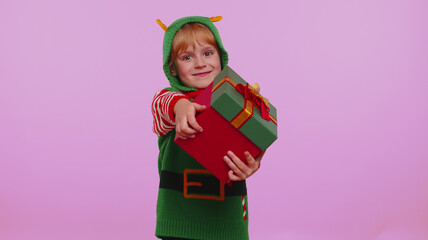 Cheerful girl in Christmas Santa helper Elf costume presenting Christmas box, excited by holiday gift, lot of presents isolated on violet background. Happy New Year celebration merry holiday concept