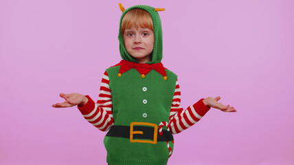 I dont know what to say. Confused girl in Christmas Santa helper Elf costume feeling embarrassed about ambiguous question, having doubts, no idea, being clueless and uncertain on violet background